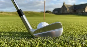 A close-up profile of a precision-milled muscle back blade iron designed for advanced golfers, resting on lush green turf.