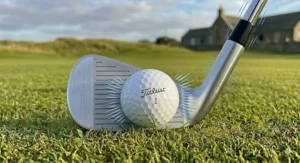 A set of timeless, polished chrome muscle back irons in a leather golf bag, reflecting traditional British golf aesthetics.