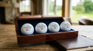 A silver presentation tin opening to reveal a set of three personalised golf balls, white wooden tees, and a custom ball marker, making a unique golf gift under 50 pounds.