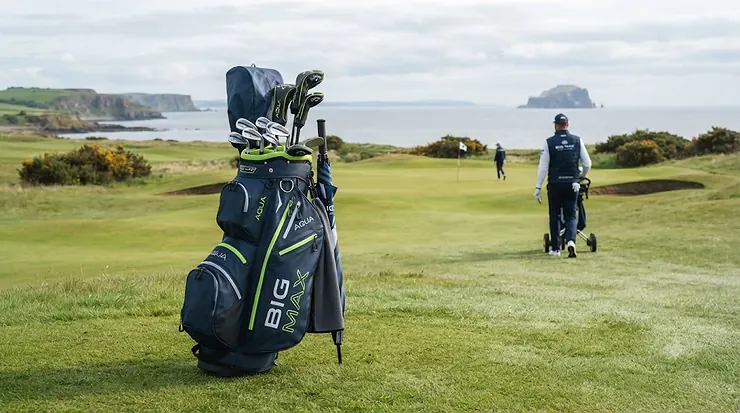 Big Max waterproof cart golf bag in sleek black, standing on a British golf course fairway under an overcast sky. Big Max golf bag