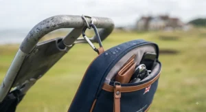 Durable metal carabiner clip securing a golf valuables pouch to the side pocket of a golf trolley.