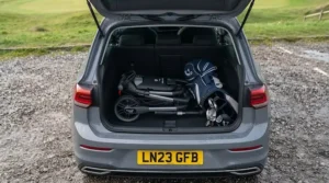 Overhead view showing a folding electric golf trolley leaving plenty of spare room in a compact car boot for a golf bag.