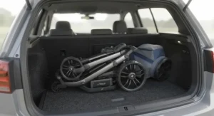 Compact folded electric golf trolley neatly stored inside the boot of a family hatchback car.