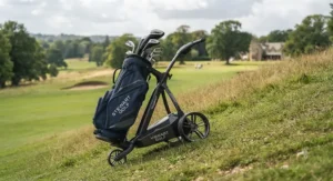 Rear stabiliser wheels on a Stewart Golf trolley maintaining balance while descending a steep fairway slope.