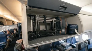 A compact push golf trolley for travel shown packed inside an aircraft overhead luggage compartment